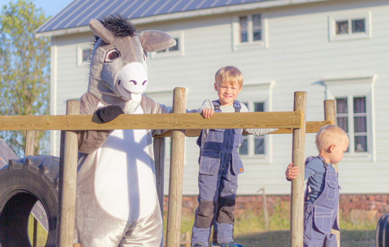 Två barn som står bredvid maskoten Åsnan